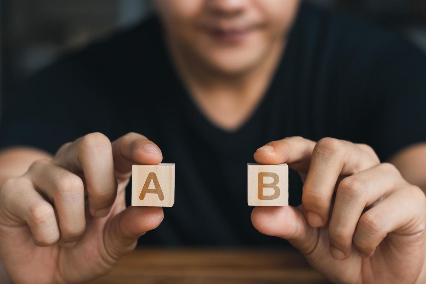 mano masculina sosteniendo un cubo de madera con ambas manos letra a y b, concepto de negocio. foto