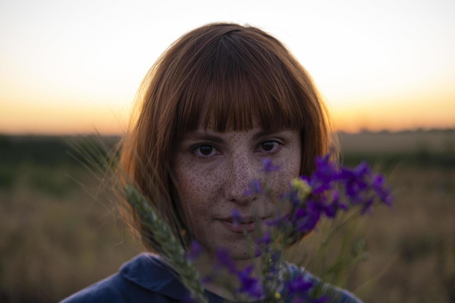 mujer joven pelirroja con pecas en vestido vintage hecho a mano caminar en campos con flores foto