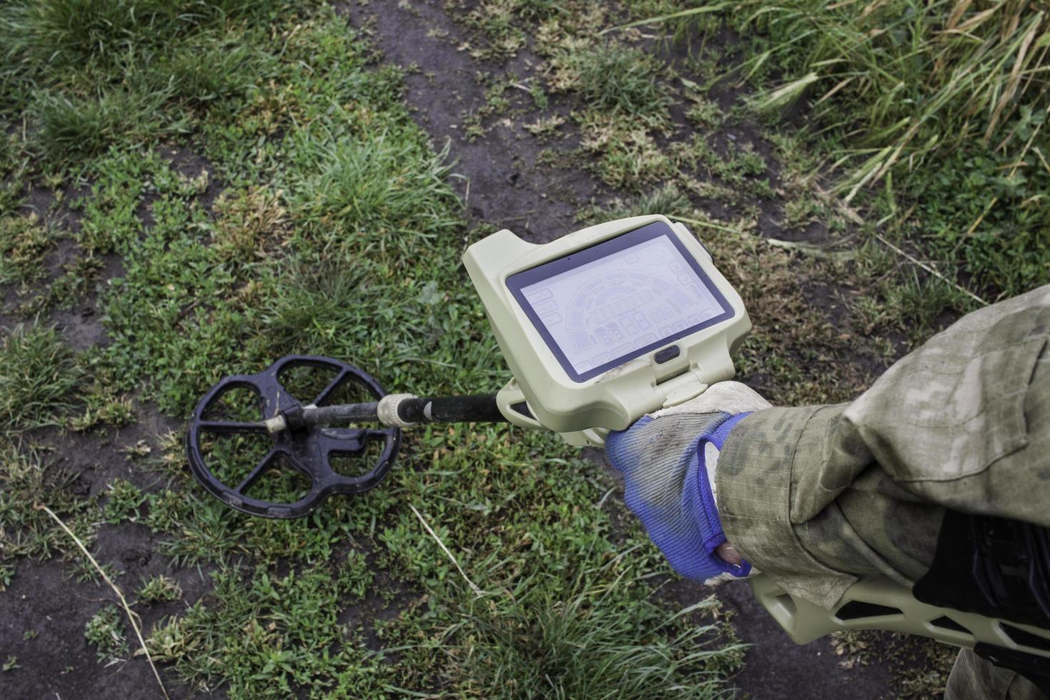 Soldier using a metal detector in fields photo