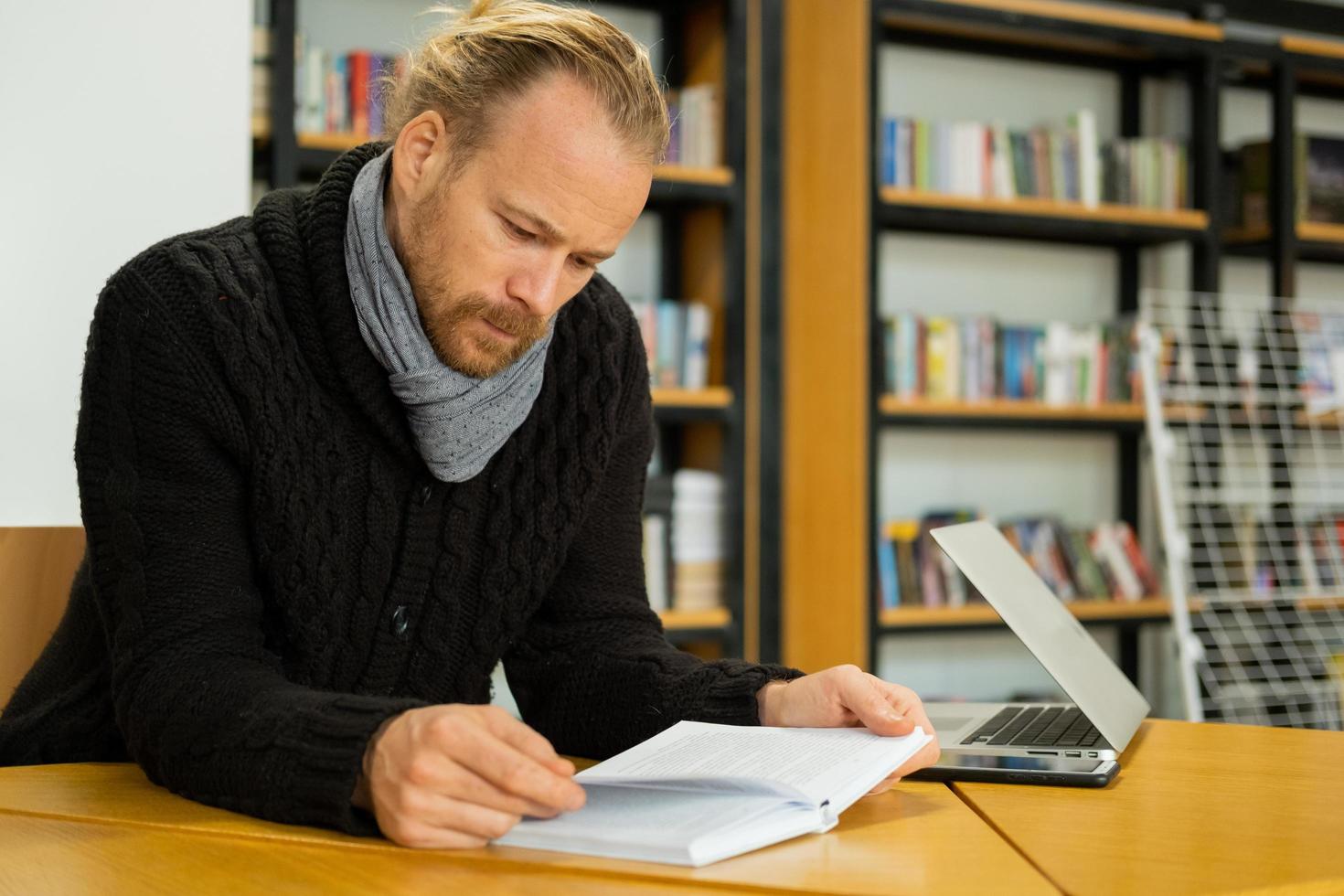 Handsome male read book and work in modern library photo