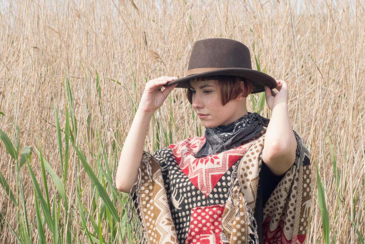 Young woman traveler in poncho and hat walk in the fields and farm photo
