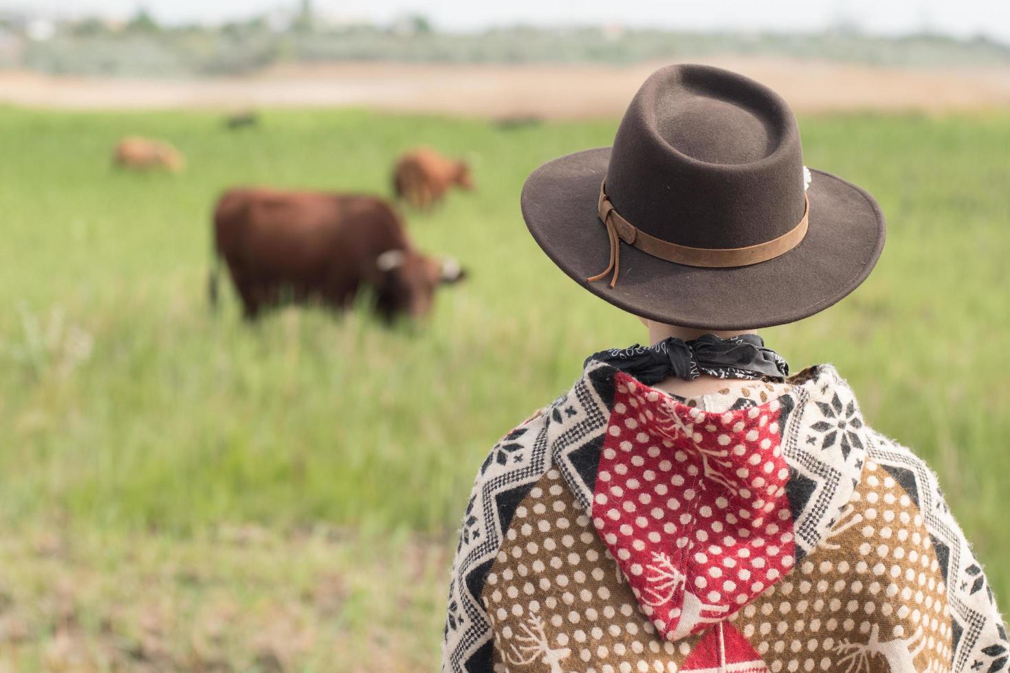 Young woman traveler in poncho and hat walk in the fields and farm photo