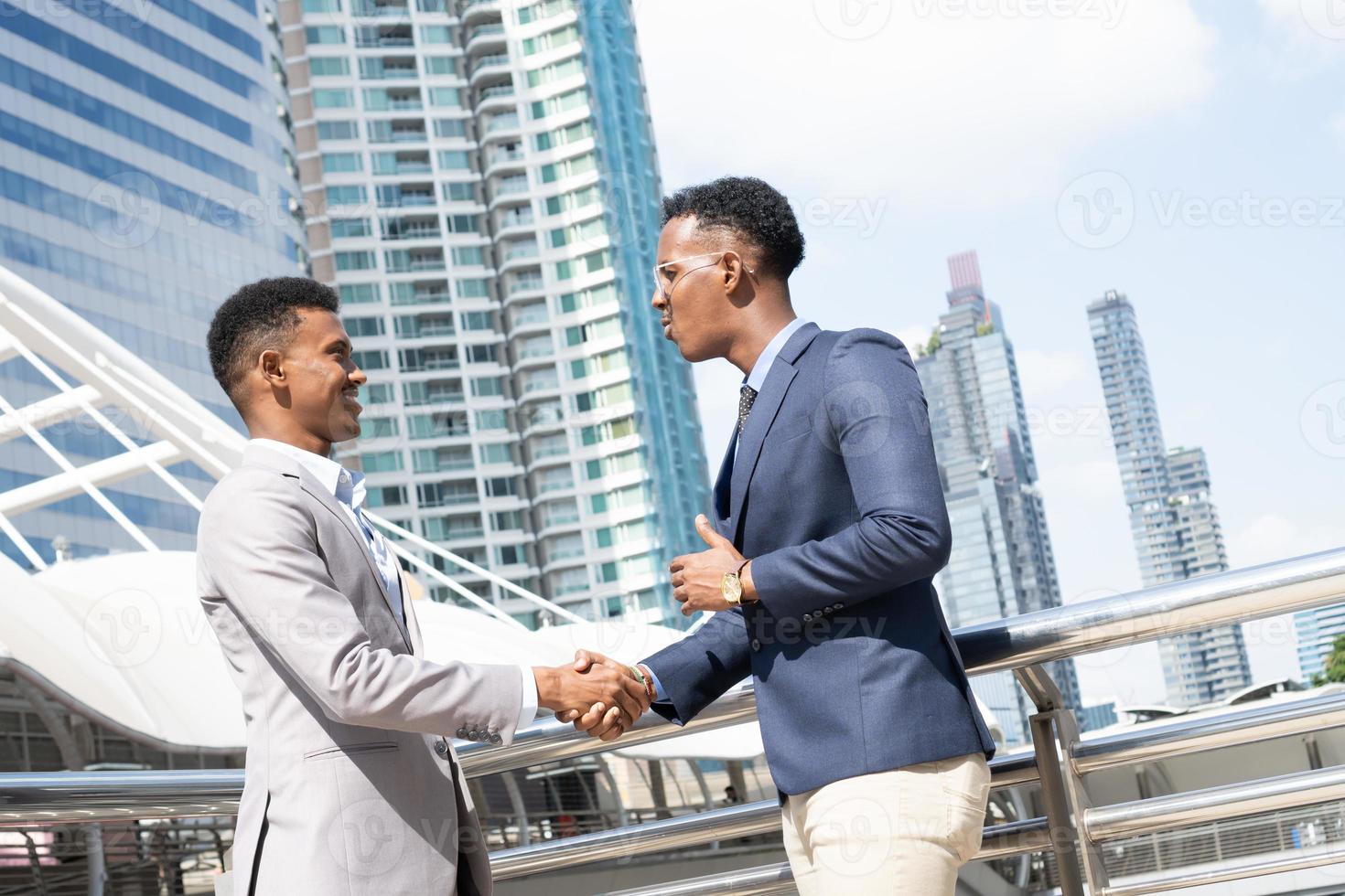 Welcome to our team. young modern men in smart casual wear shaking hands. Two smiling businessmen shaking hands together. Two confident businessmen shaking hands at the outside of the office. photo
