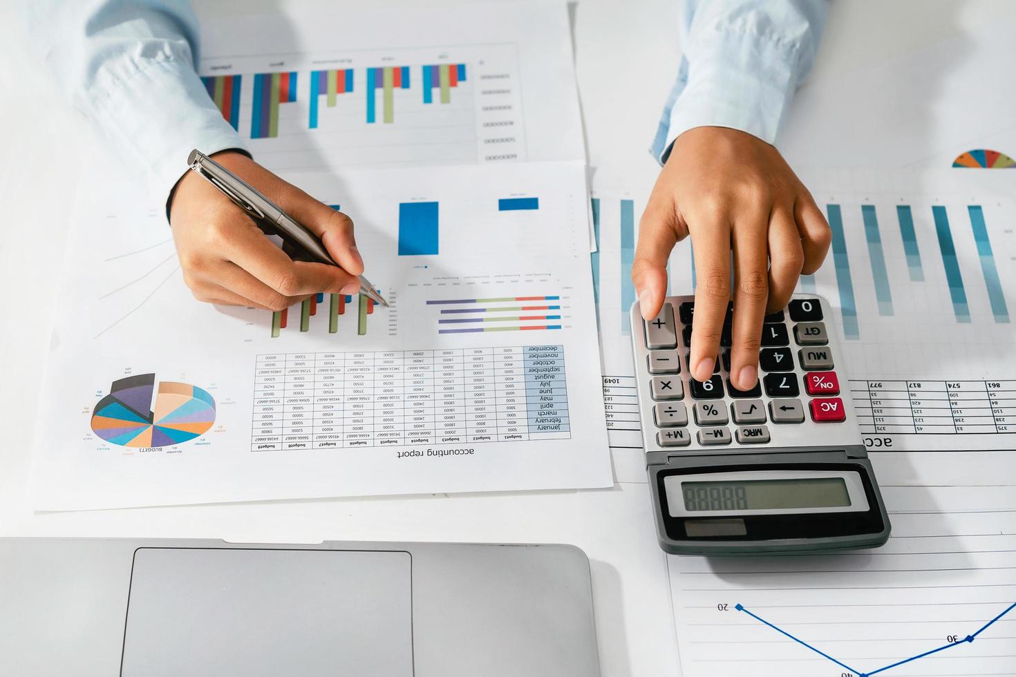 Woman accountant use calculator and computer with holding pen on desk in office. finance and accounting concept photo