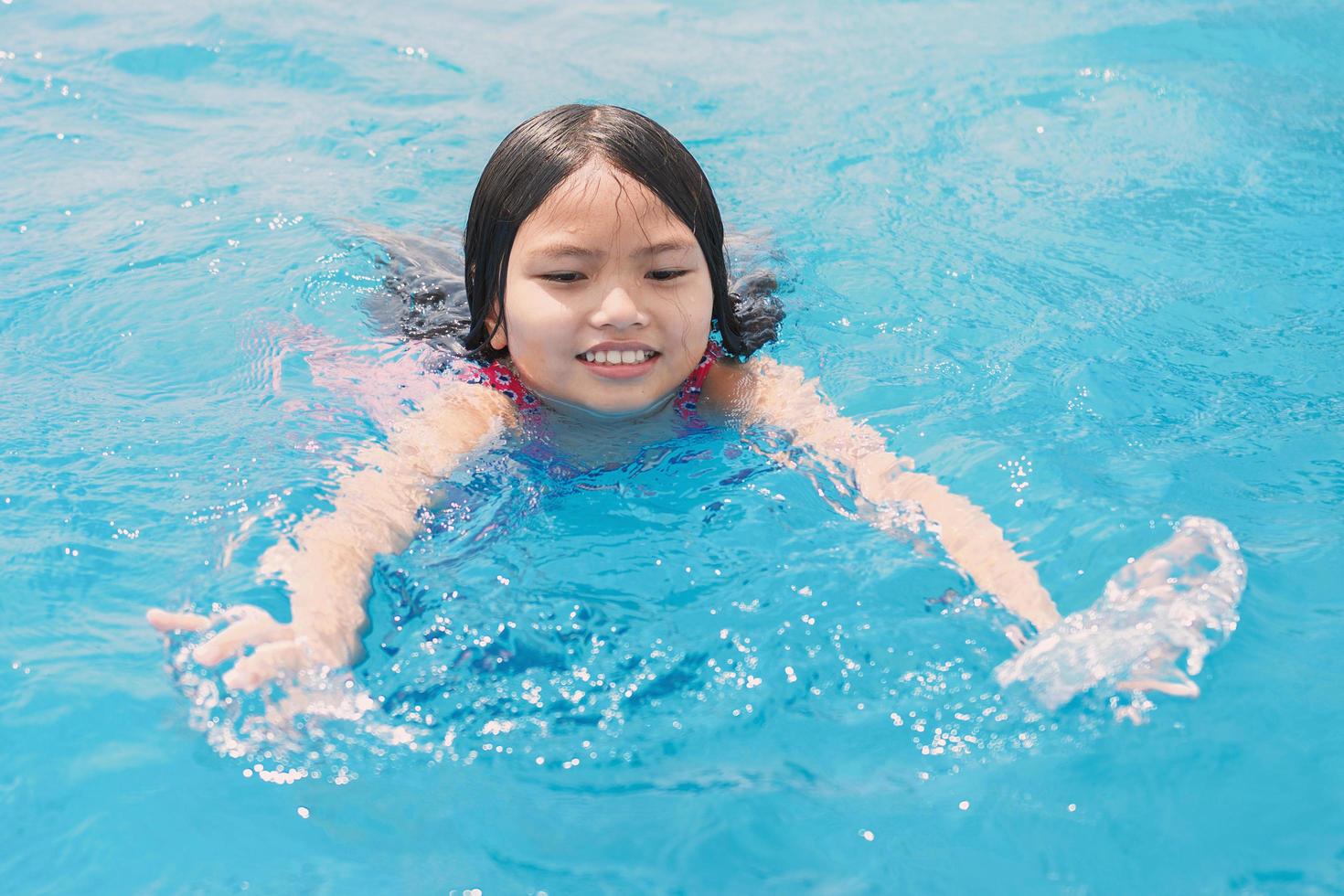 children swiming and playing in the pool with happy smile photo