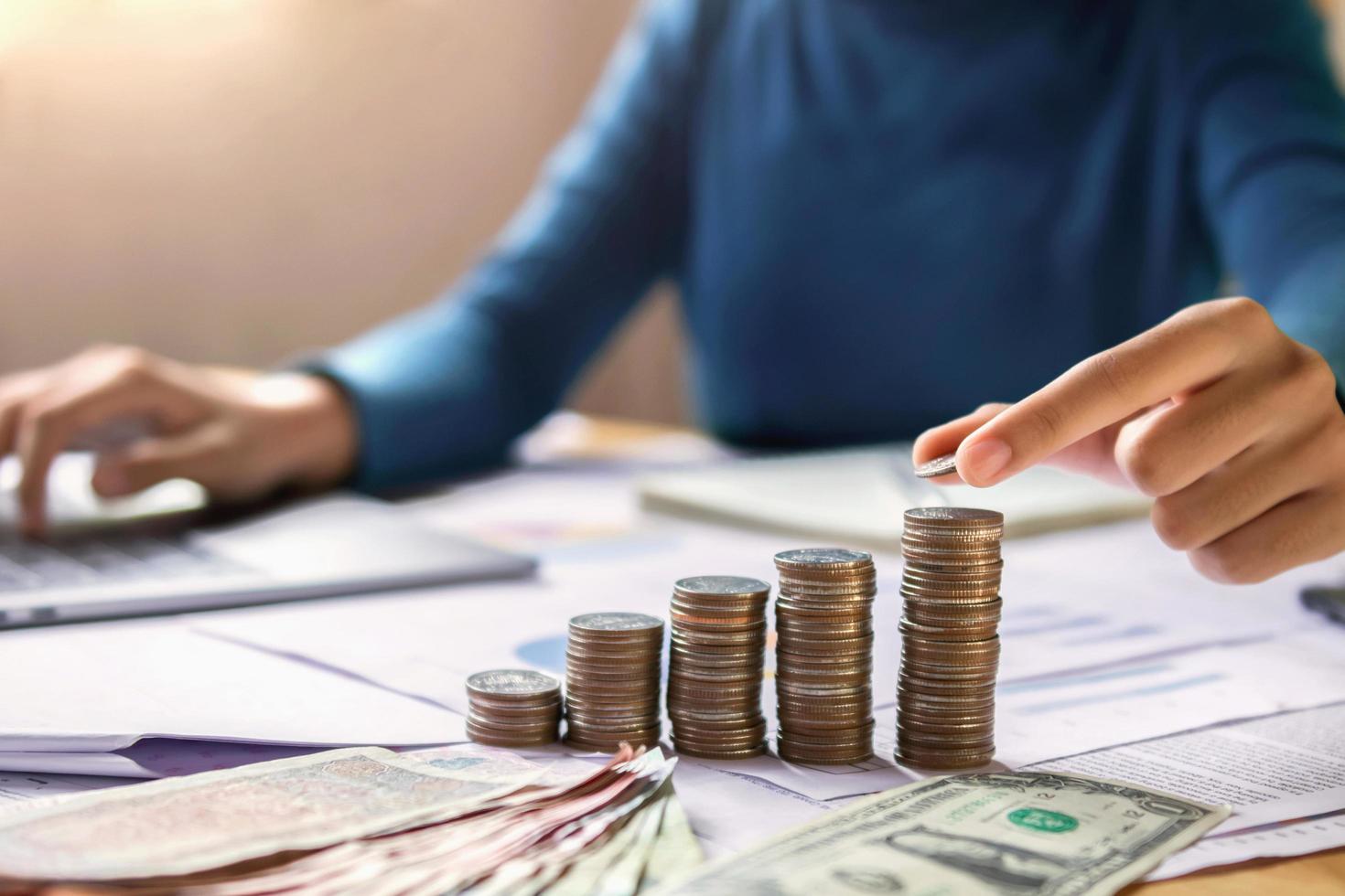 mujer de negocios mano sosteniendo monedas para apilar en el concepto de escritorio ahorrar dinero finanzas y contabilidad foto