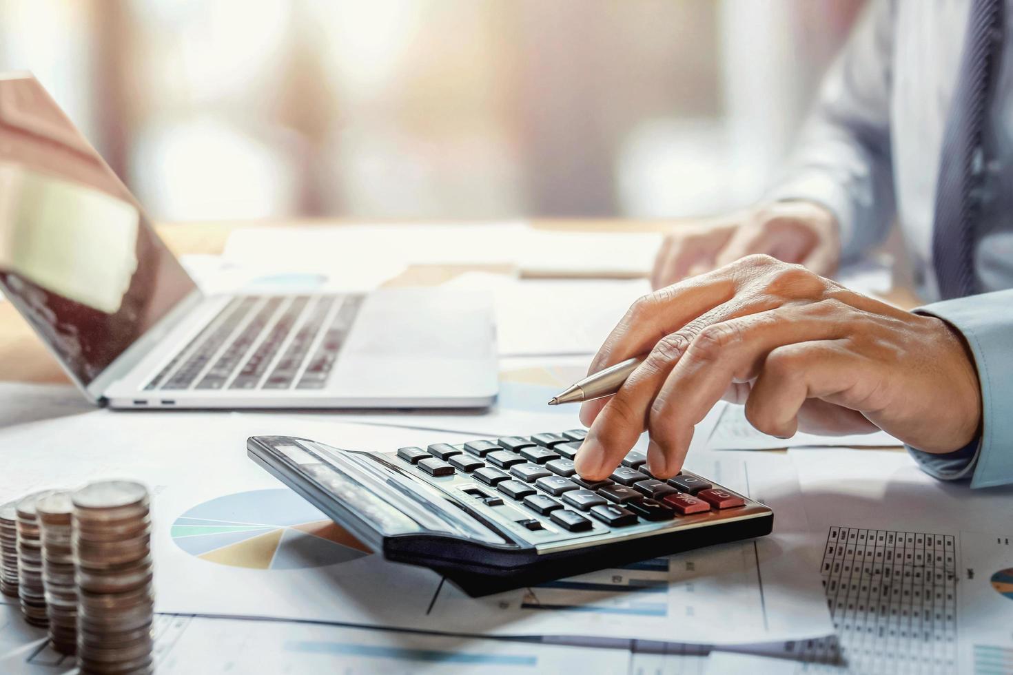 hombre de negocios que trabaja en el escritorio usando una calculadora para calcular las finanzas y la contabilidad en la oficina foto
