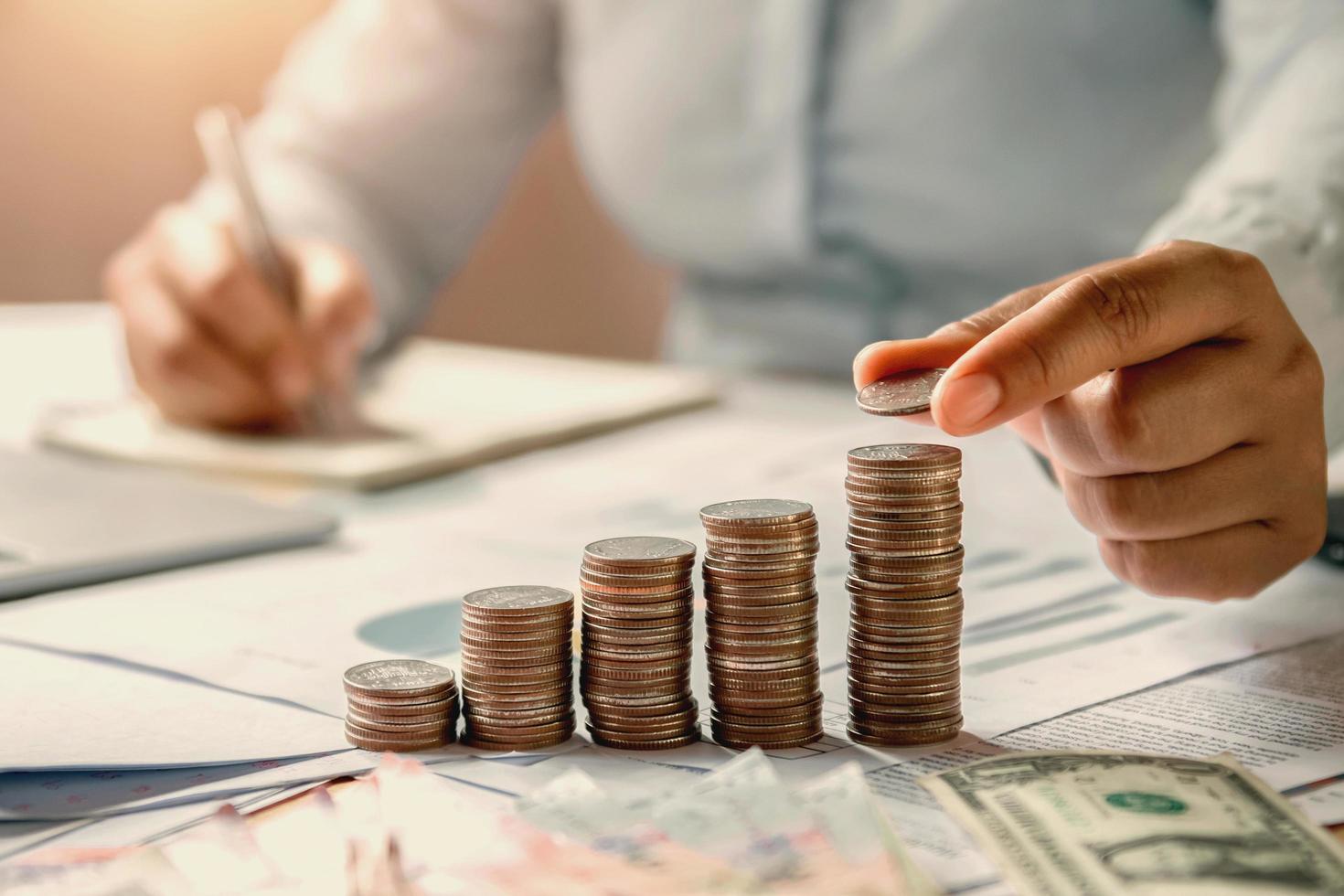 business woman hand holding coins to stack on desk concept saving money finance and accounting photo