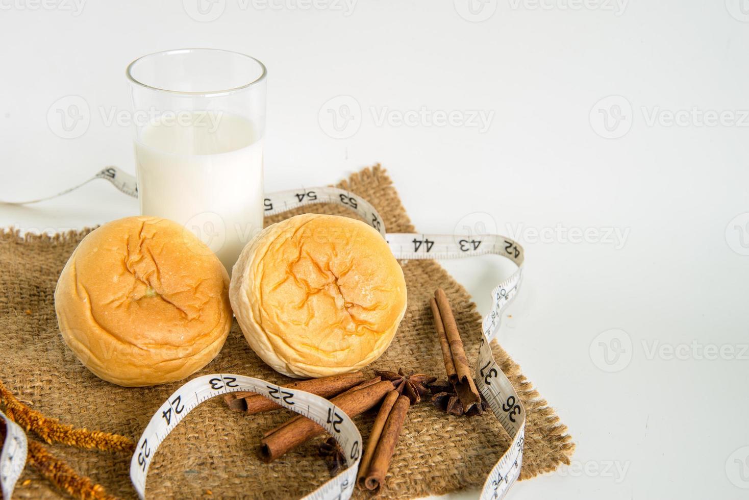milk and bread with measuring tape for diet on white background photo