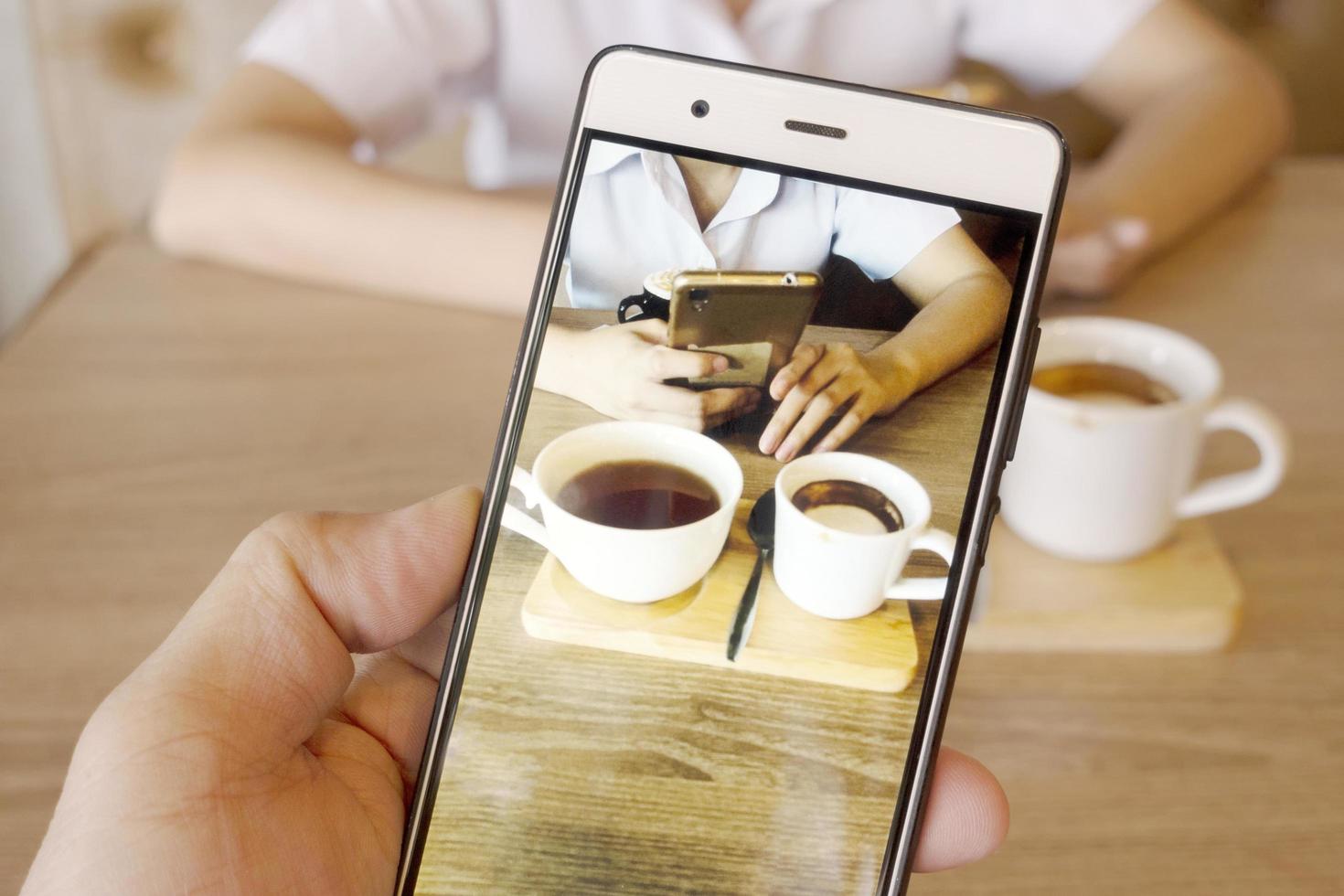 Coffee in her hand on a mobile phone. photo