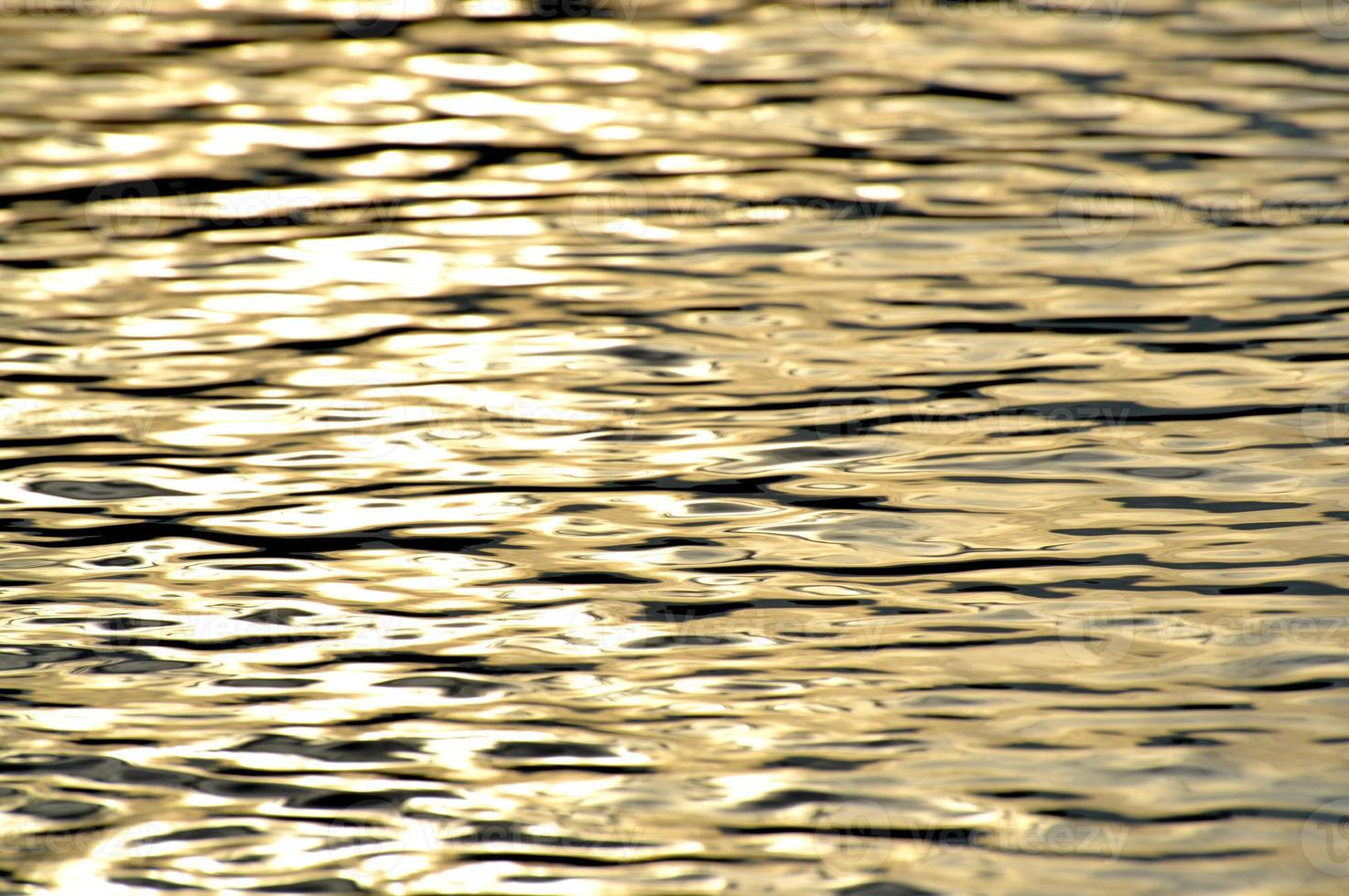 agua dorada del océano, fondo fotográfico. hermoso mar de verano, puesta de sol. fondo natural de la superficie del océano. telón de fondo para elementos de letras, tarjetas, pancartas, diseño y decoración foto