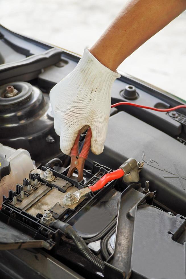 Mechanic is using electric car battery charger through jumper wires.Repair service People occupation and business job photo