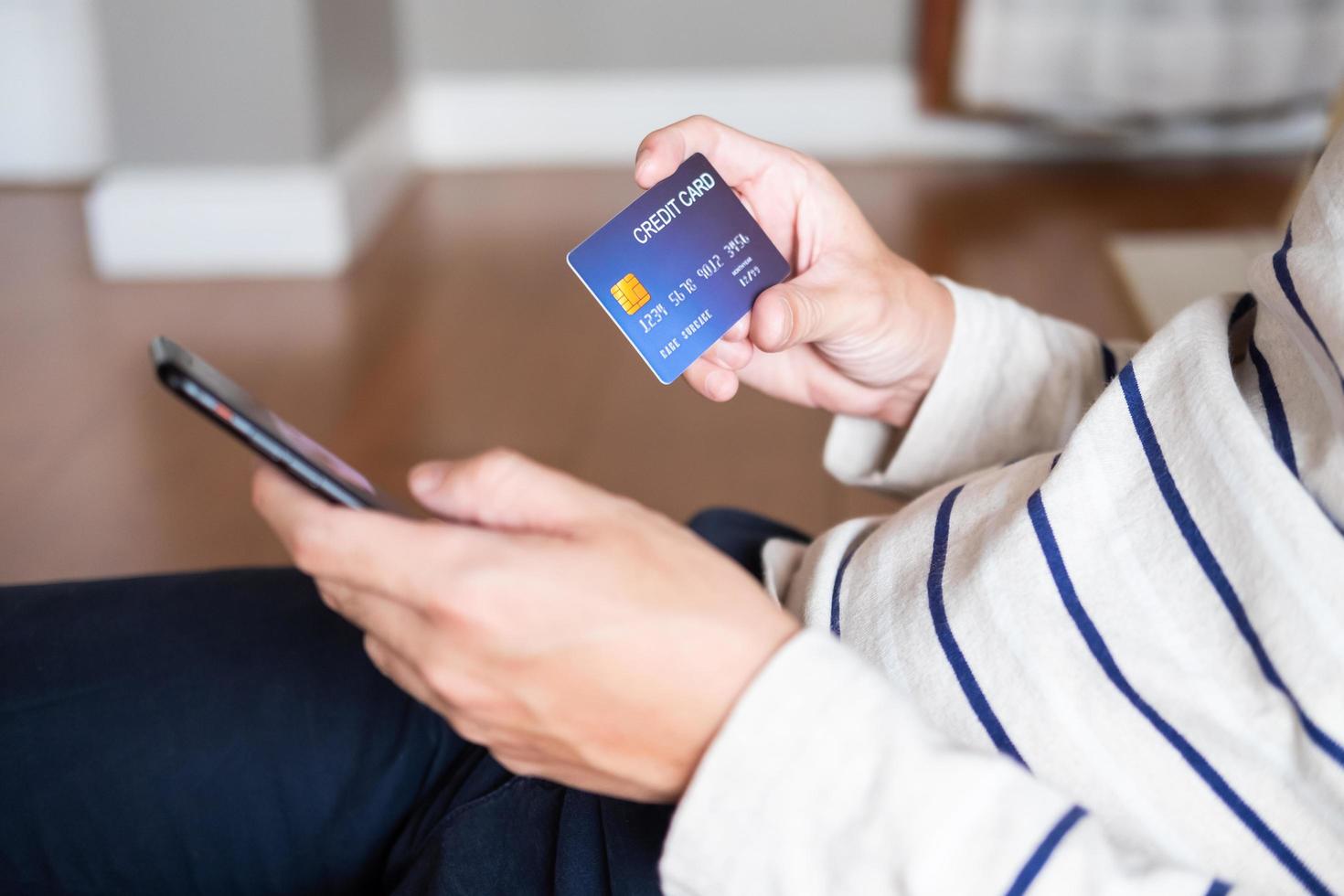 Selective focus at men hand holding mobile phone. Close up shot at men while enter security key on credit card for online payment shopping. Wireless banking transaction via internet technology. photo