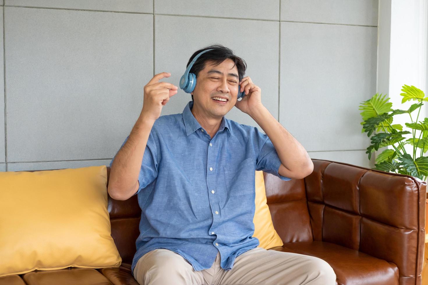 Senior Asian grandfather enjoy and feeling happy while listening music from wireless headphone that streaming music from smartphone or tablet device. Elderly retirement lifestyle with good health. photo