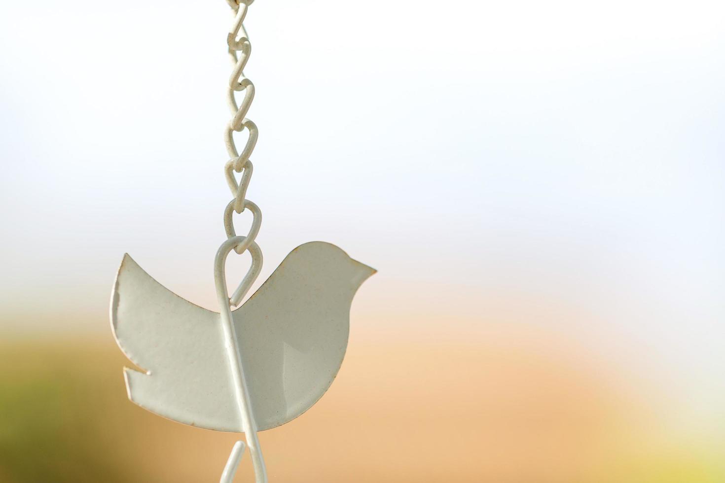 Close-up shape bird wind chime with hanging chains photo