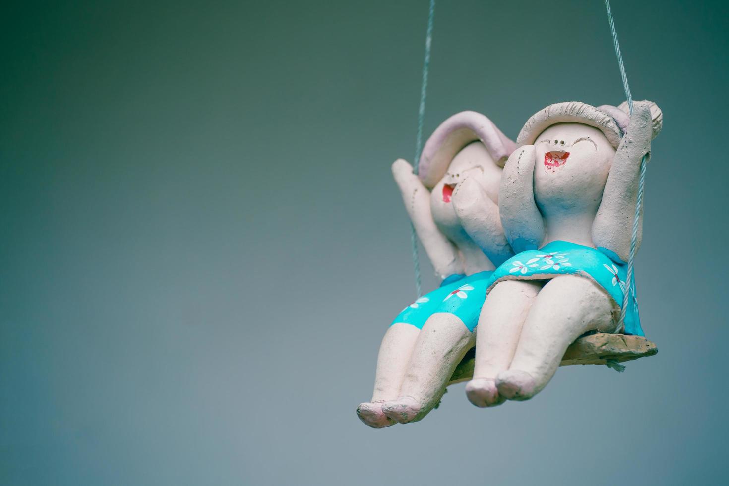 Clay child dolls sitting on swings in home, Concept of decoration and garden arrangement. photo