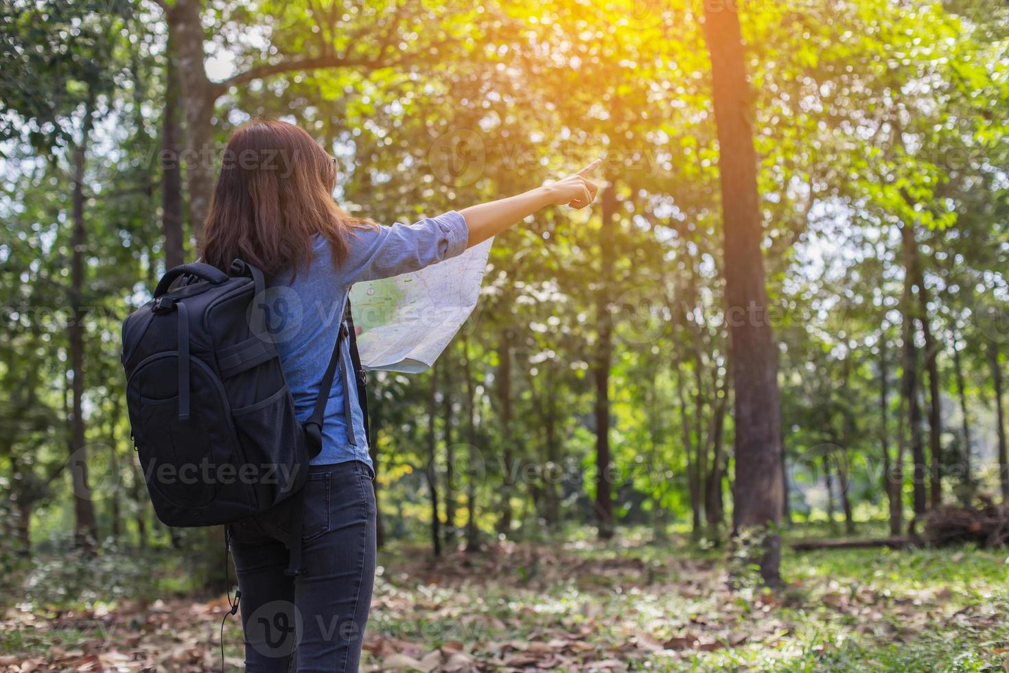 Women hiker with backpack checks map to find directions in wilderness area photo