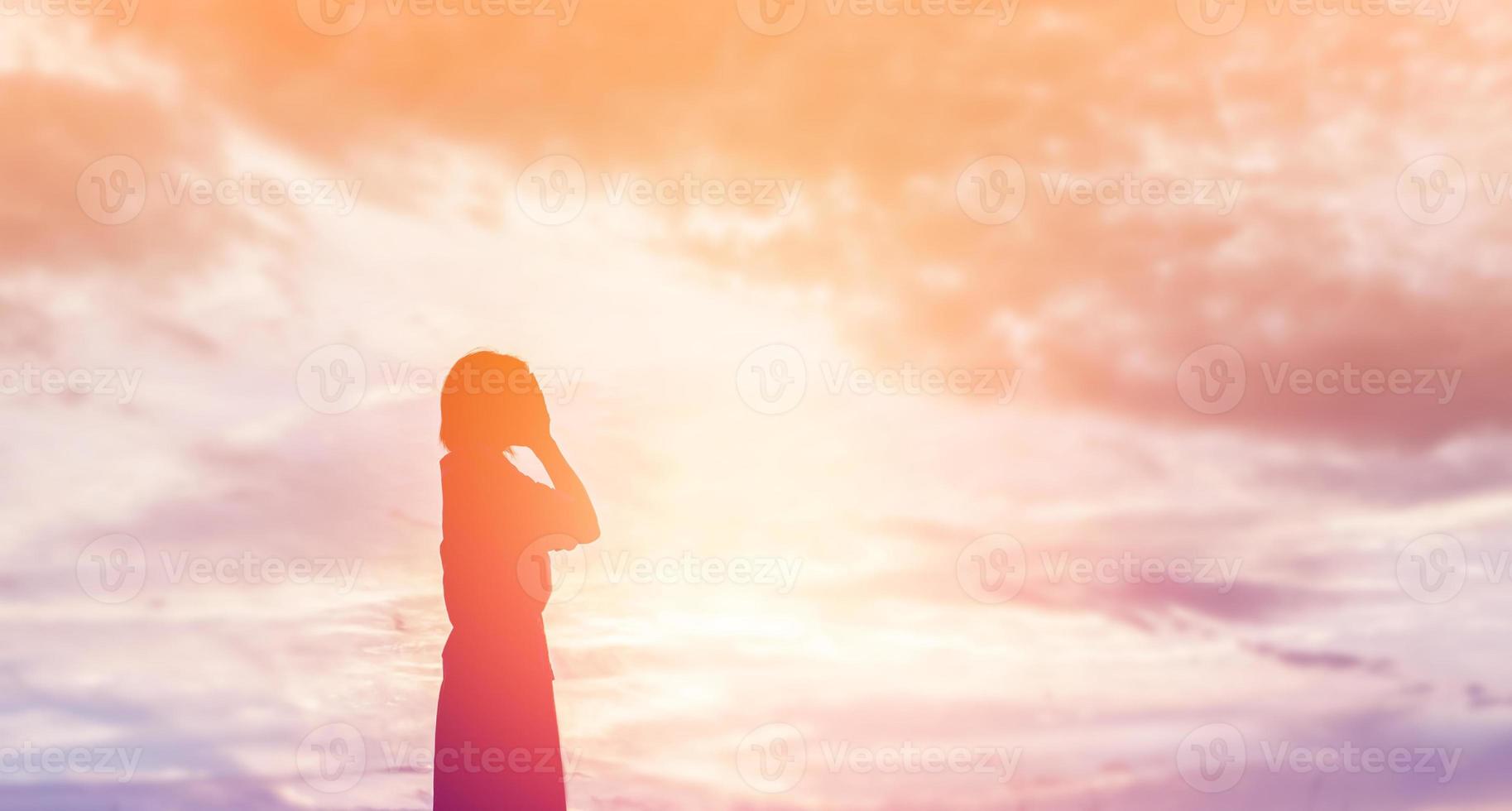 Silhouette of woman praying over beautiful sky background photo