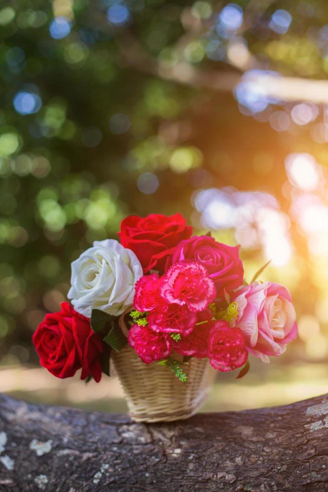 Mixed beautiful flowers in the vase on wooden background photo