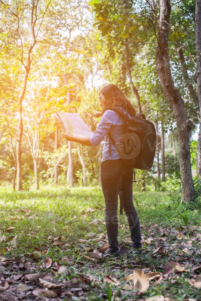 Women hiker with backpack checks map to find directions in wilderness area photo