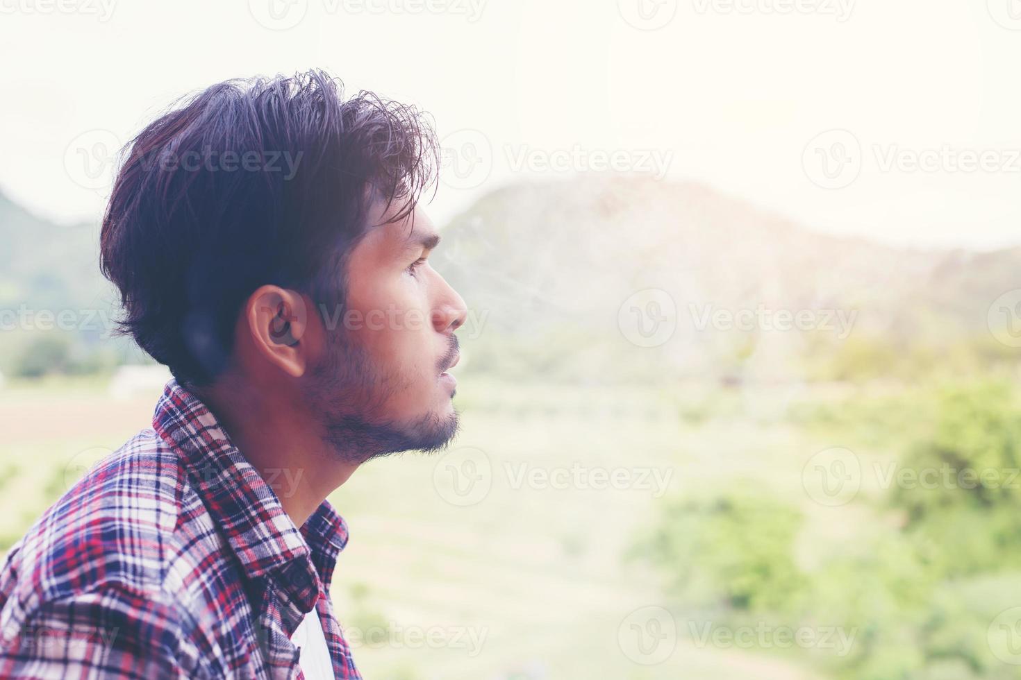 Hipster man smoking cigarette, standing behind a mountain. Among the fresh air in the morning. photo