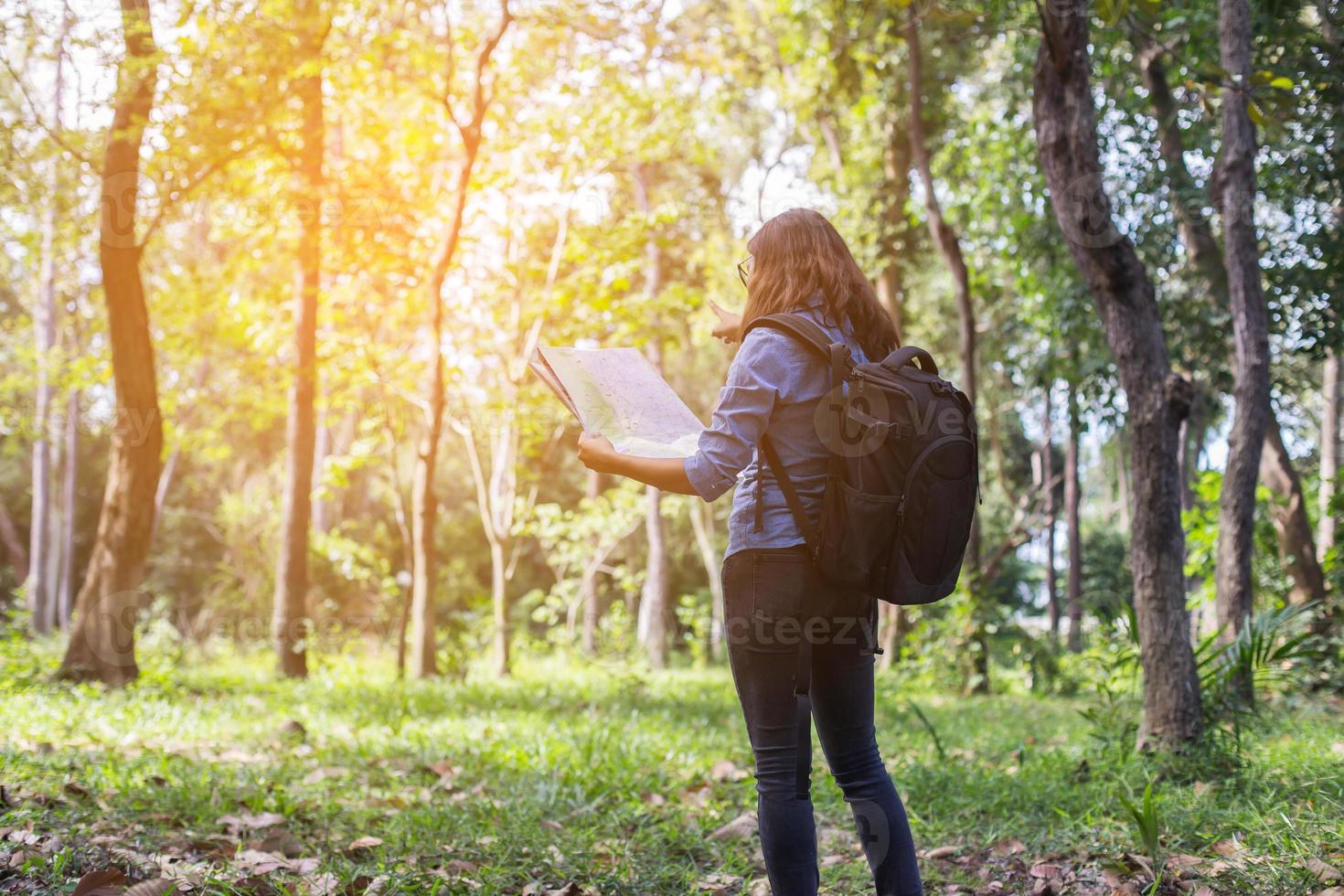 Women hiker with backpack checks map to find directions in wilderness area photo