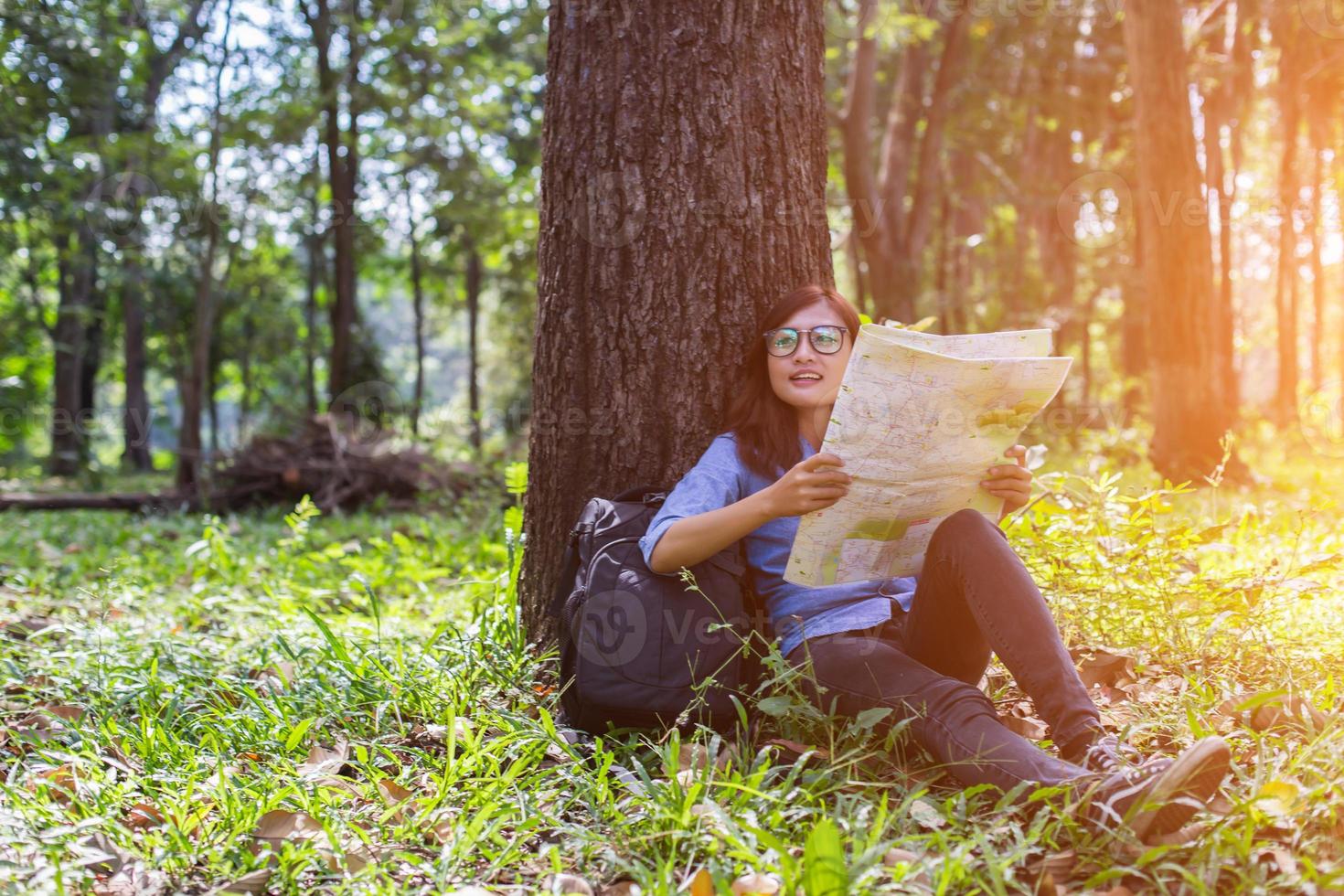 Women hiker with backpack checks map to find directions in wilderness area photo