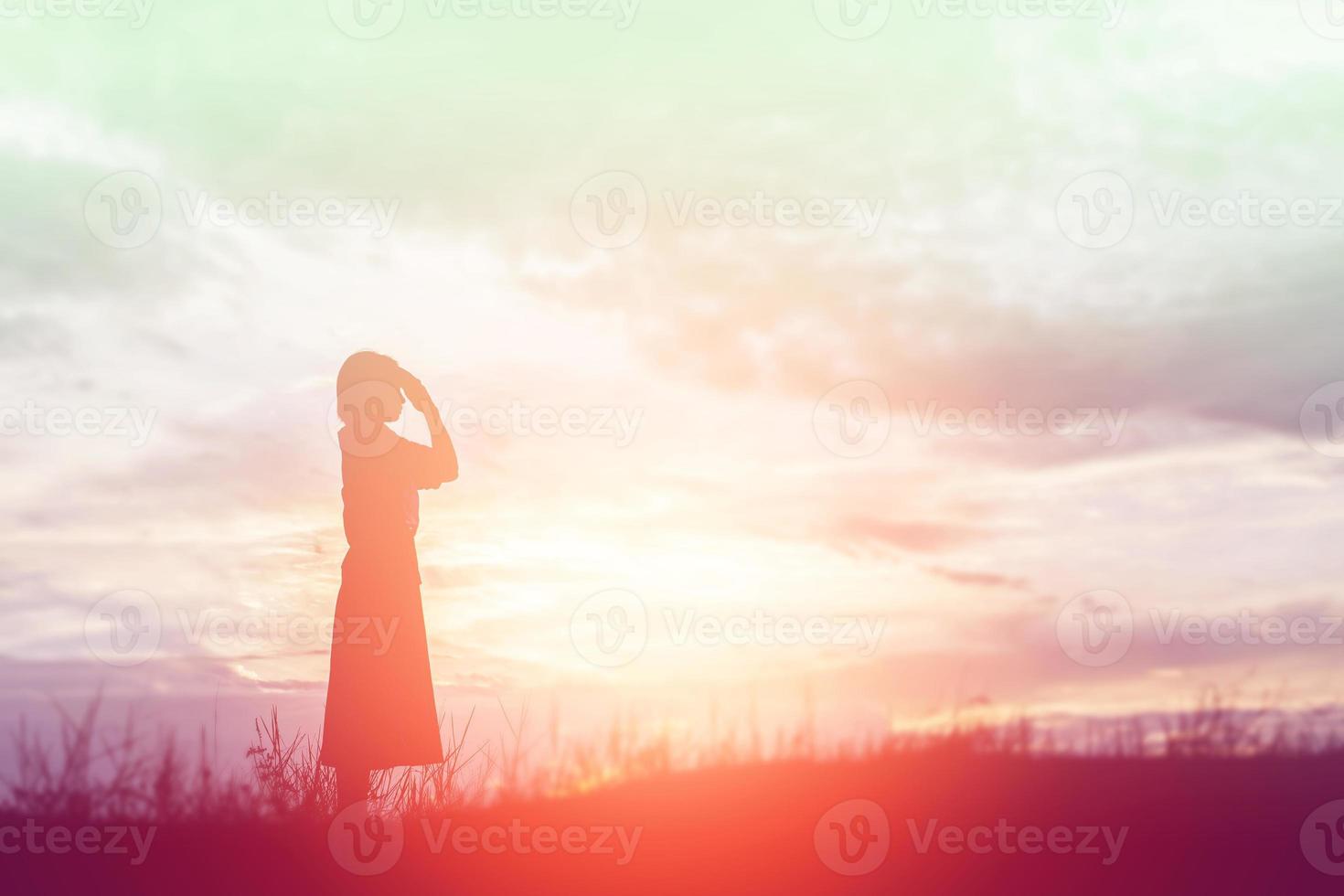 Silhouette of woman praying over beautiful sky background photo