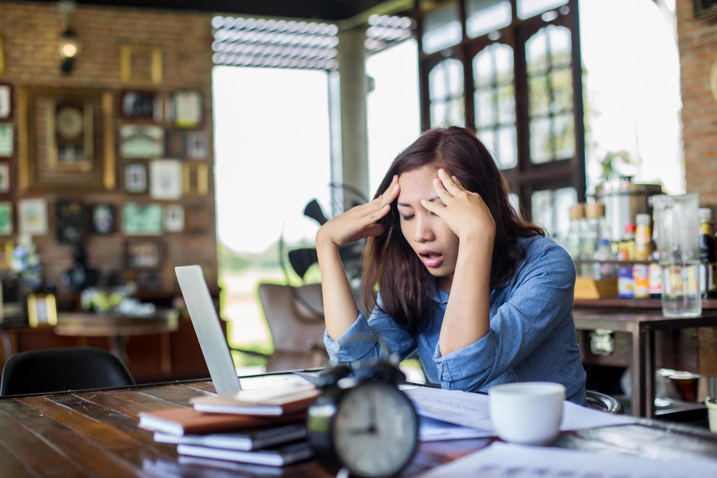 Young woman sitting in a cafe with her laptop, Stressful for work. photo