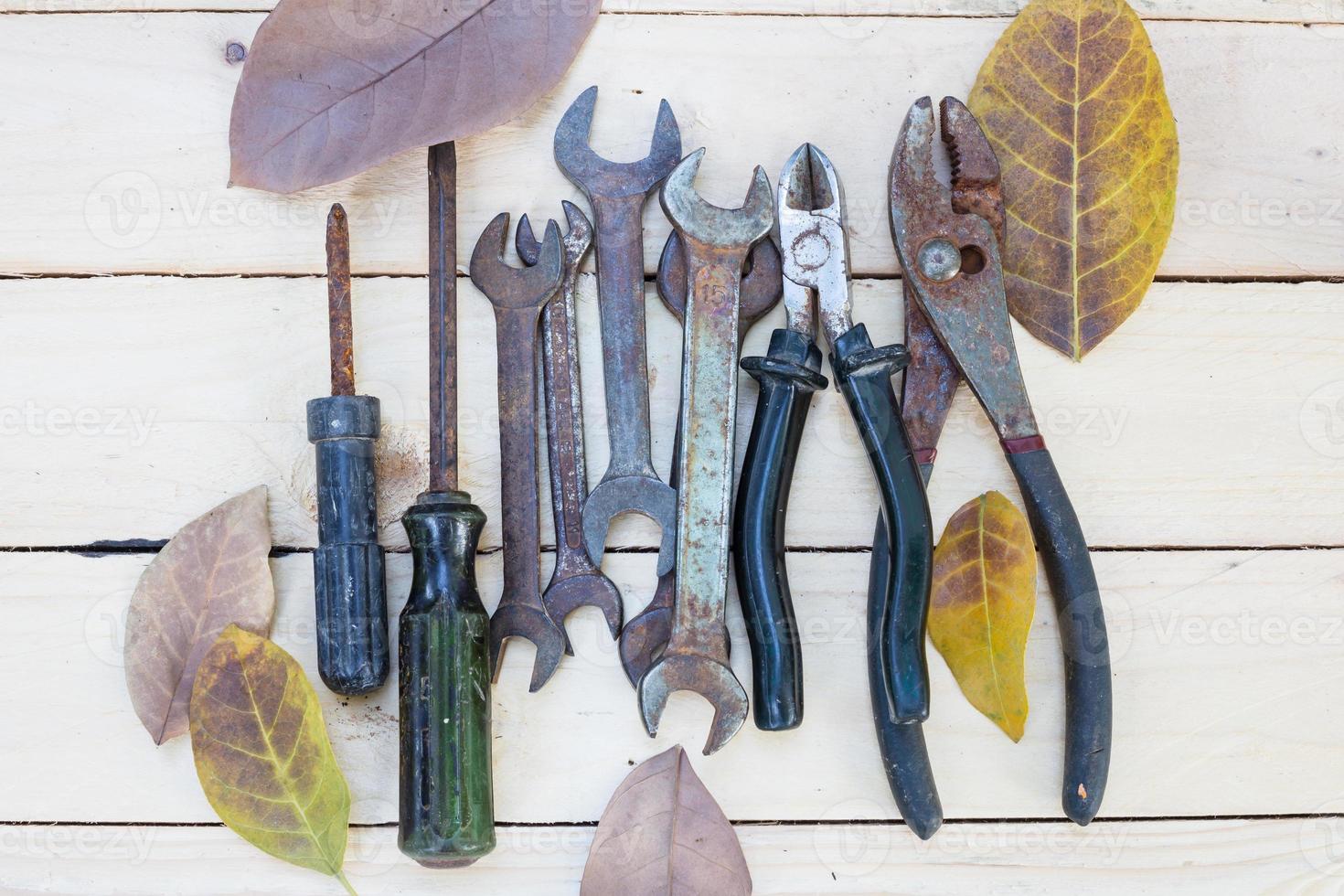 Tools and dried leaves on wooden table photo