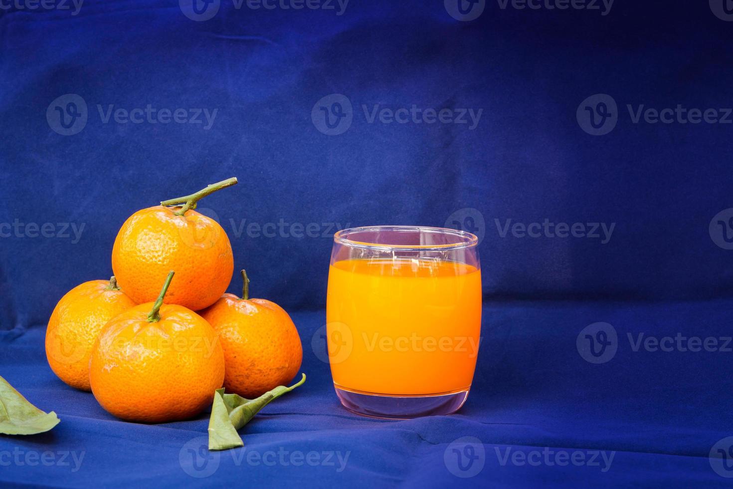 vasos de jugo de naranja y frutas con hojas secas foto