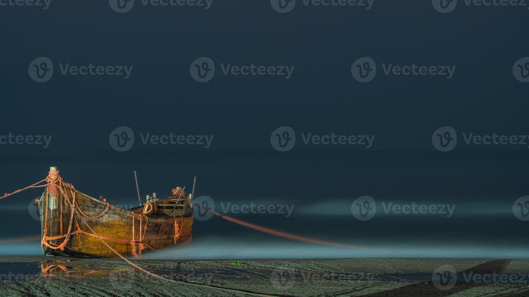 Long exposure of an old boat on the beach by the moving waves of the ocean photo