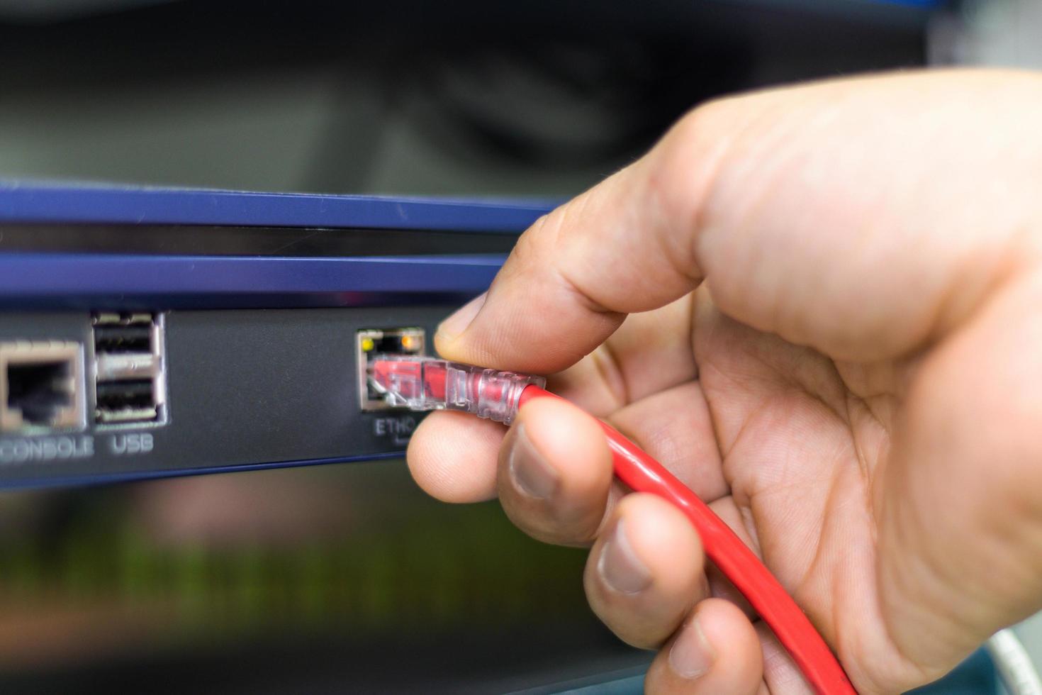 mano de un hombre que sostiene los cables de red para conectar el puerto de un conmutador para conectar la red de Internet, tecnología de comunicación conceptual foto