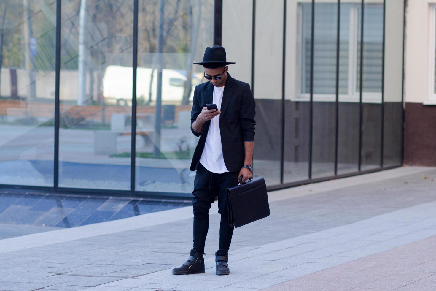 joven hombre feliz con traje negro y sombrero negro, concepto de hombre de negocios moderno foto