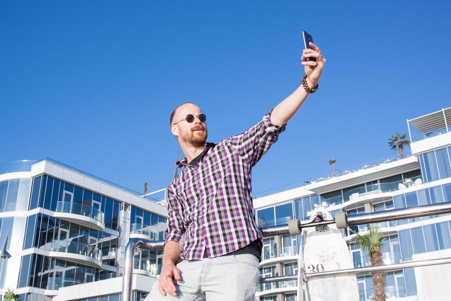 joven barbudo se hace selfie por teléfono foto