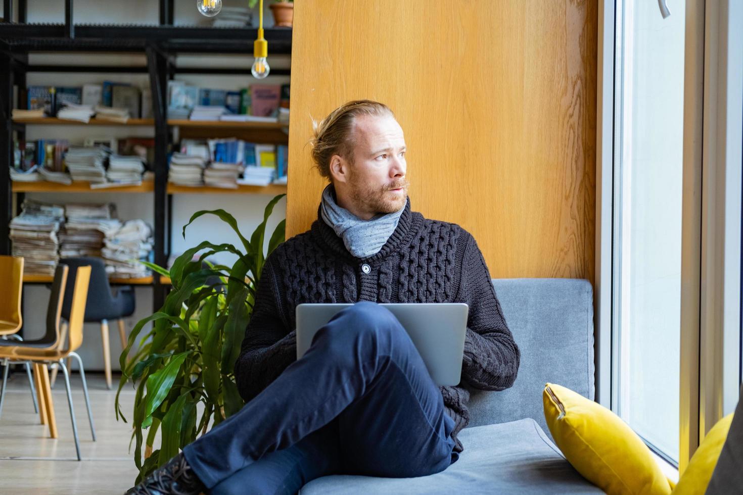 un hombre guapo lee un libro y trabaja en una biblioteca moderna foto