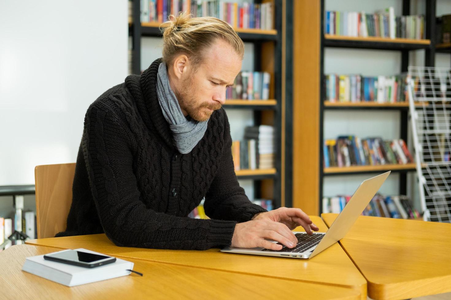 Handsome male read book and work in modern library photo