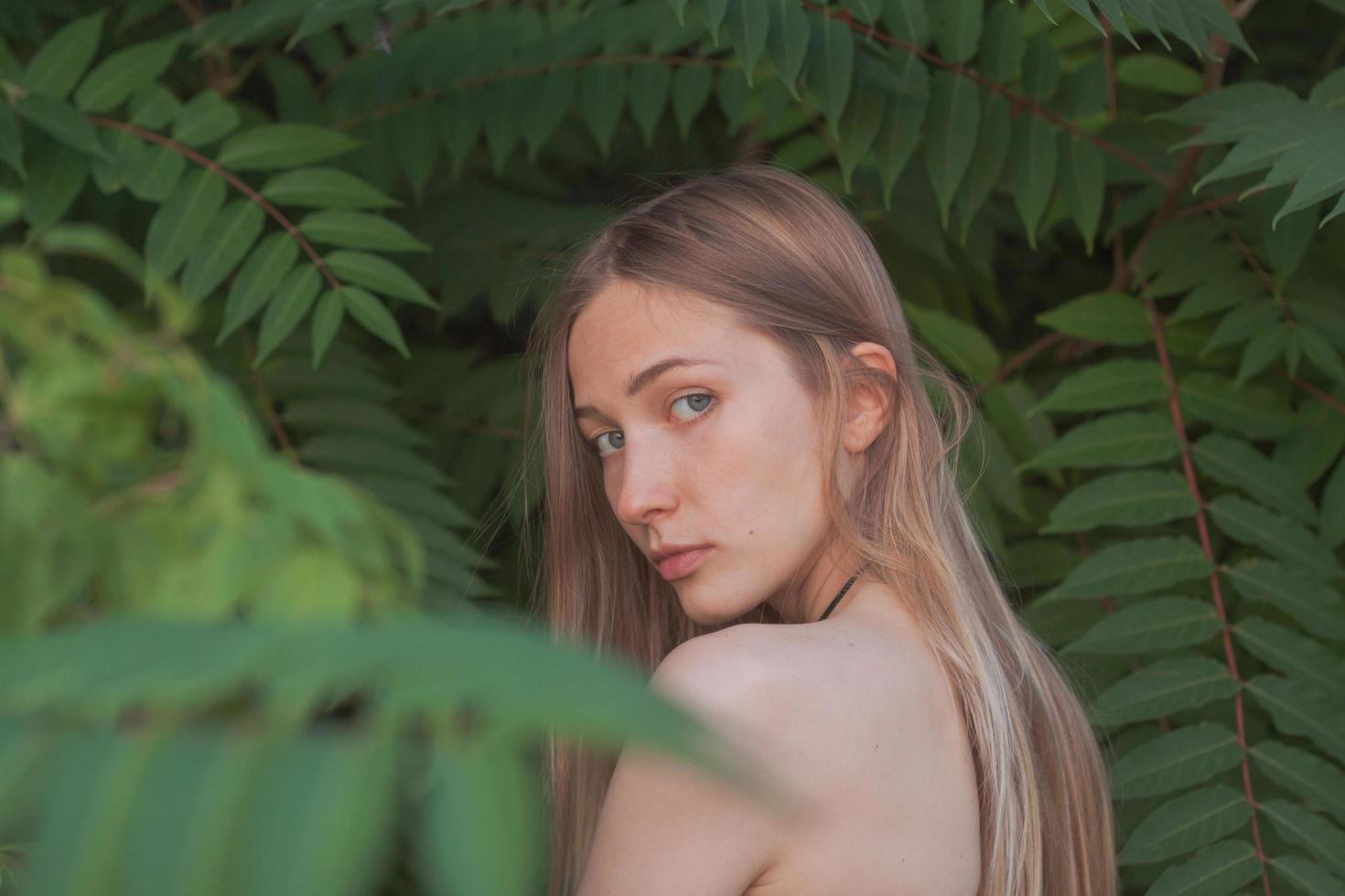 Portrait of beautiful young woman in green leaves, blonde pretty lady in spring bushes photo