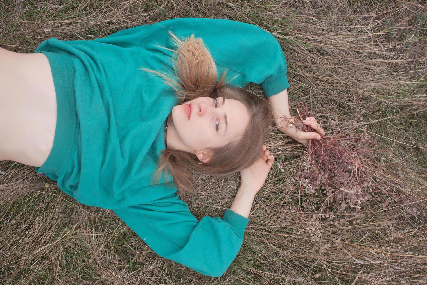 Young woman in fields, portrait of beautiful female relaxing in dry grass photo
