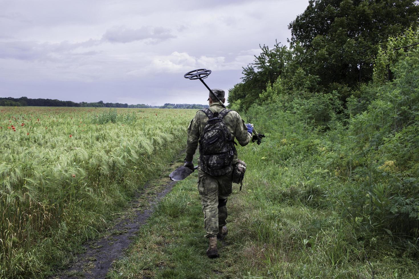 Soldier using a metal detector in fields photo