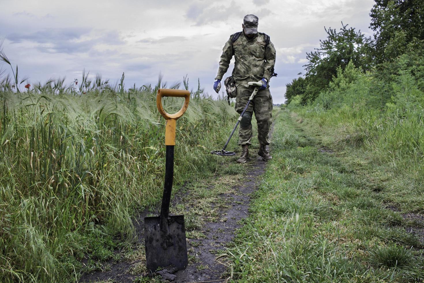 Soldier using a metal detector in fields photo