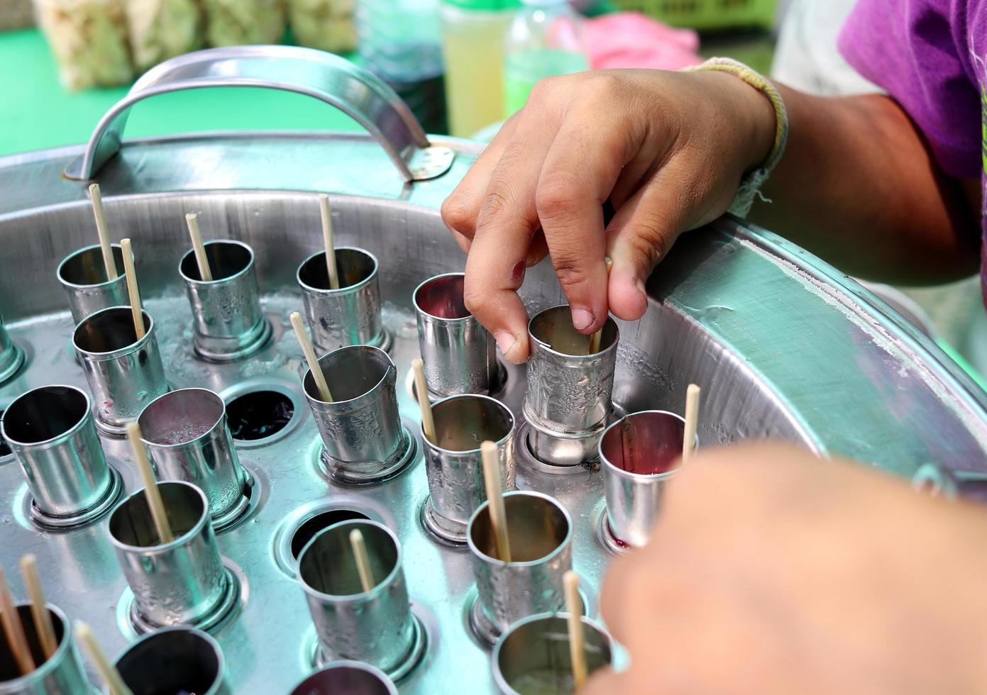 Bamboo sticks in stainless tubes are making ice cream. Hand is checking ice cream in tube,Thailand. photo