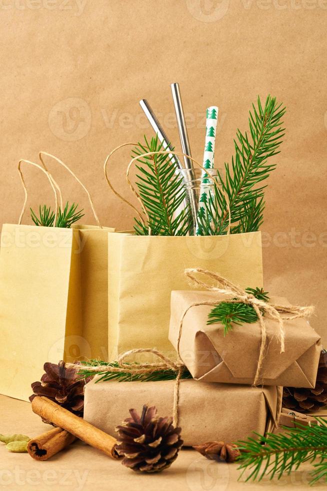 Christmas and Happy New Year zero waste craft paper backdrop. Handmade gift Christmas box, fir branches, reusable straw,, side view, copy space. Ecofriendly plastic free concept photo