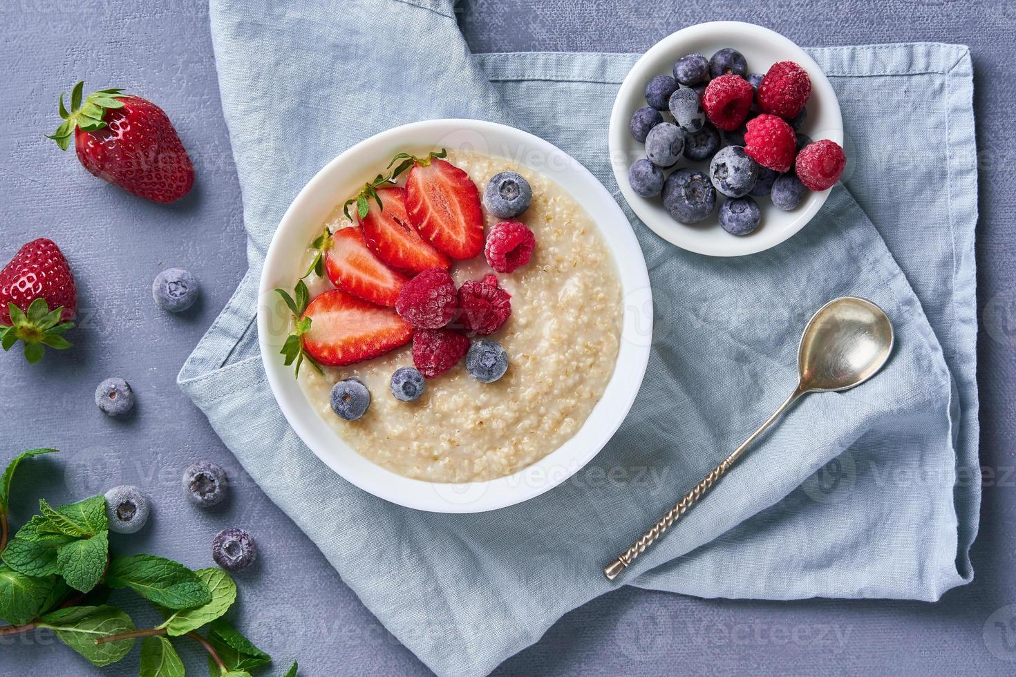 avena con arándanos, fresas, frambuesas sobre fondo azul oscuro foto