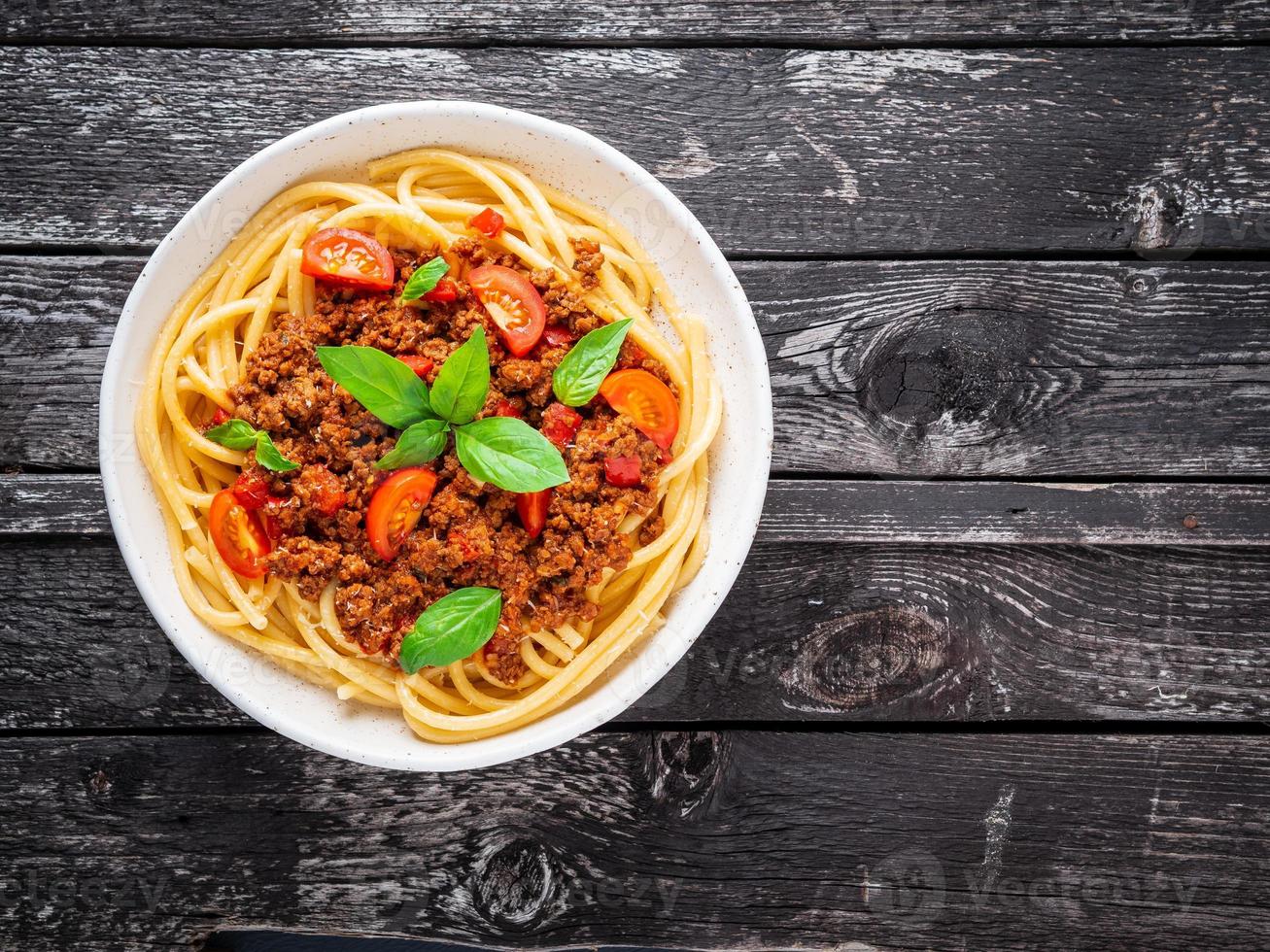 pasta boloñesa con salsa de tomate, carne picada molida, hojas de albahaca en el fondo foto