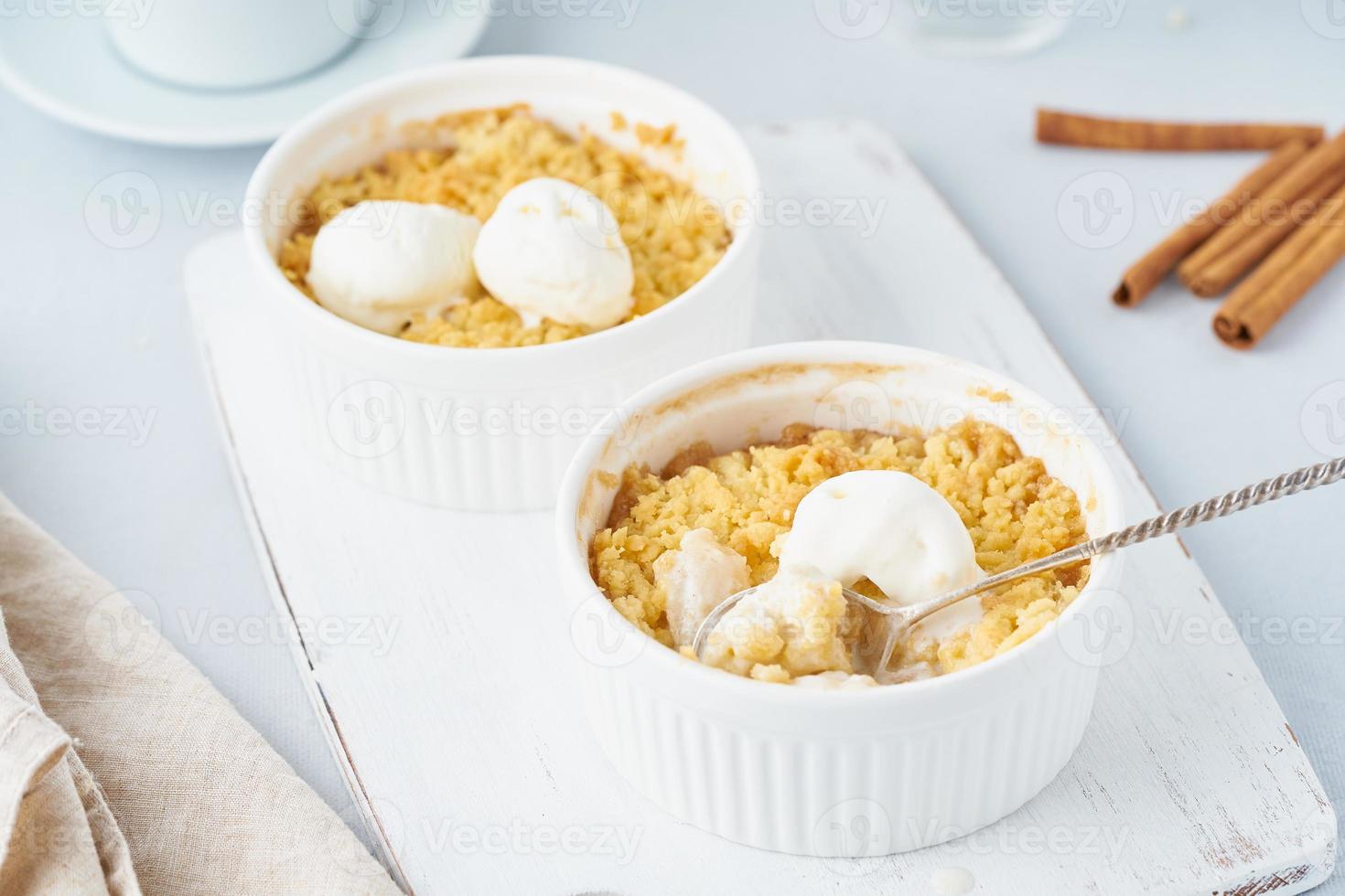 crumble de manzana con helado, cuchara con streusel. desayuno matutino en una mesa gris claro foto