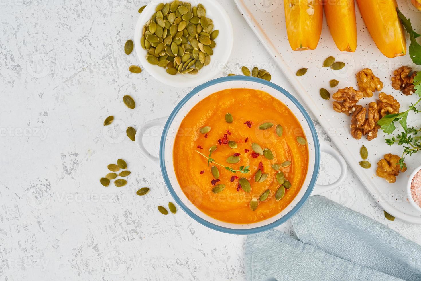 Pumpkin cream soup with seeds, top view light white background copy space photo