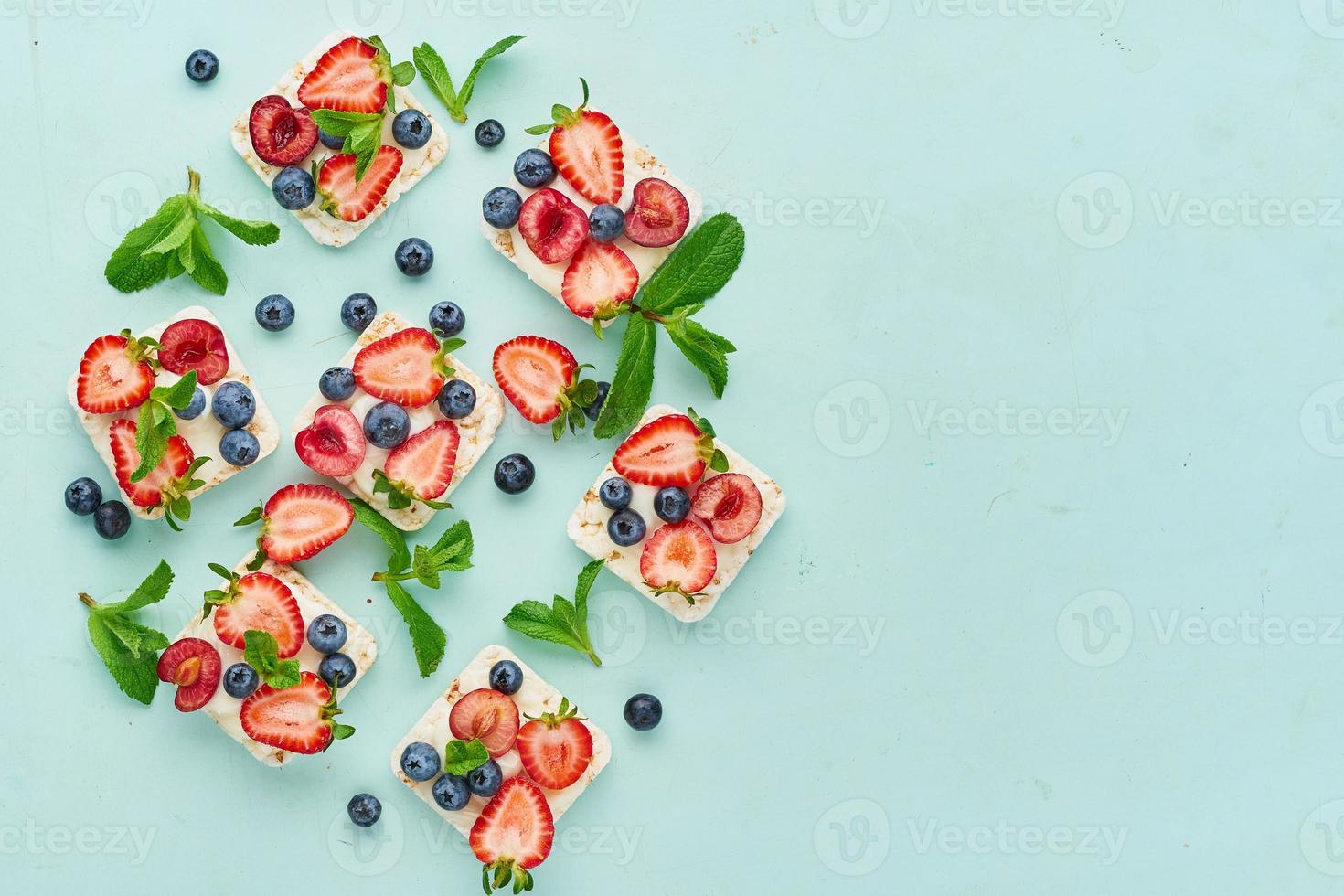 Rise crispbread with berries and fruits colorful concept on turquoise aquamarine background photo