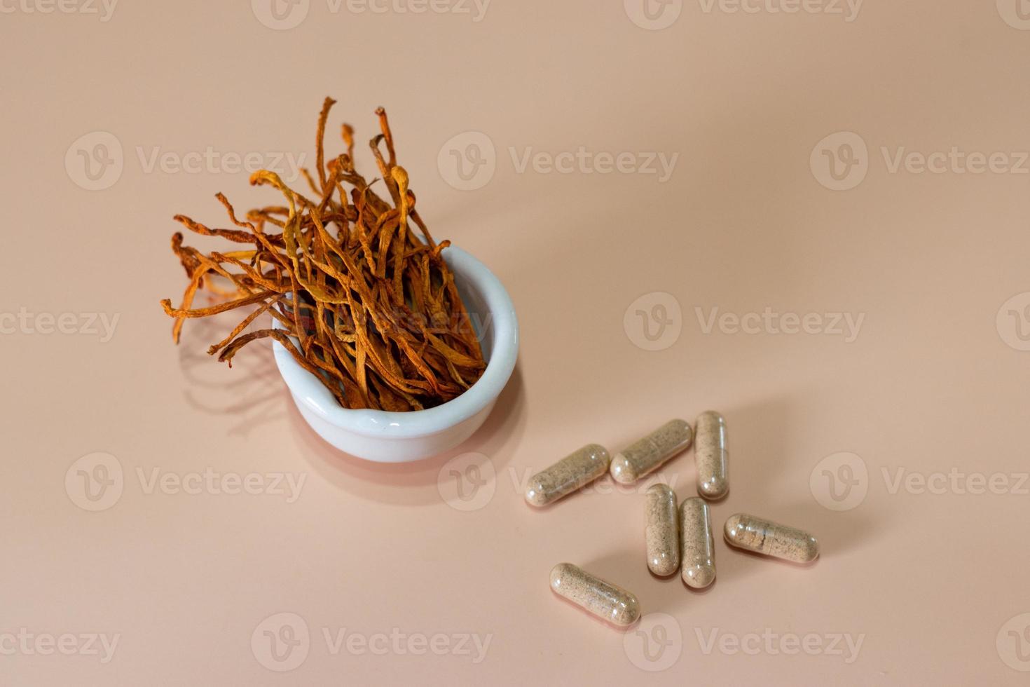 Dry cordyceps militaris mycelium in white bowl with wooden background. Orange medical mushroom for good health. photo