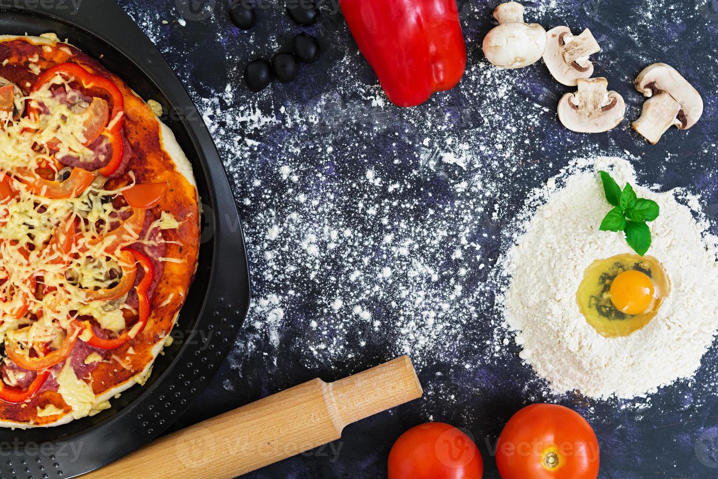 masa de pizza cruda con ingredientes y especias sobre fondo oscuro. vista superior foto